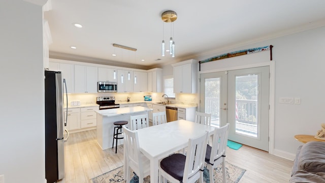 dining room with light hardwood / wood-style floors, crown molding, french doors, and sink