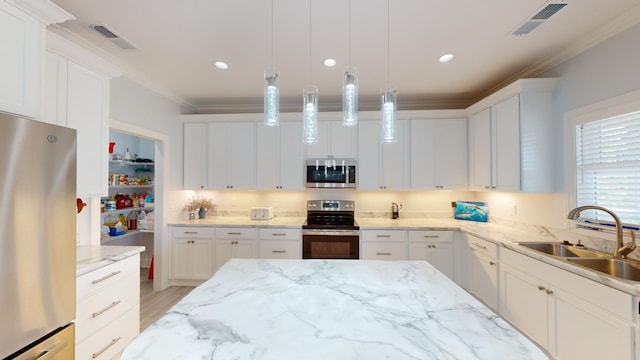 kitchen with white cabinets, hanging light fixtures, ornamental molding, appliances with stainless steel finishes, and light stone countertops