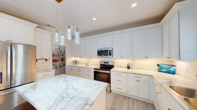 kitchen with white cabinets, stainless steel appliances, light hardwood / wood-style floors, and a center island