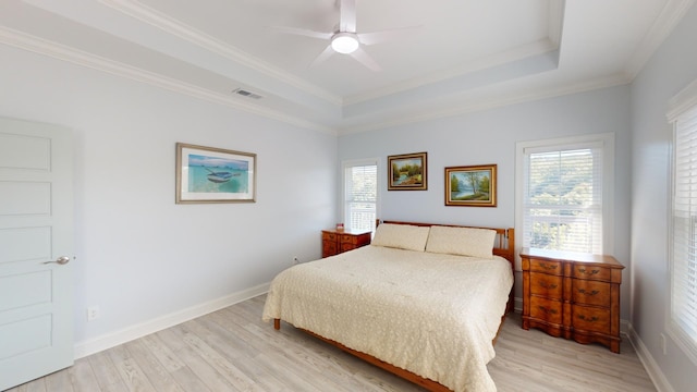 bedroom with ornamental molding, a tray ceiling, light hardwood / wood-style floors, and ceiling fan