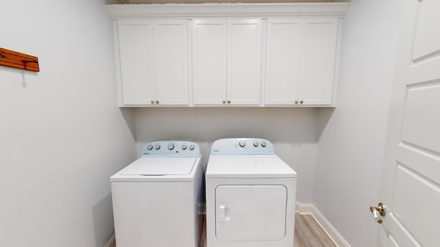 laundry area with cabinets, light wood-type flooring, and washer and dryer