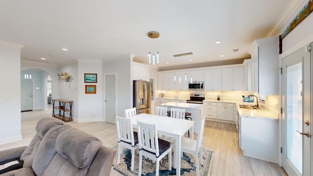 dining room featuring ornamental molding, sink, and light hardwood / wood-style floors