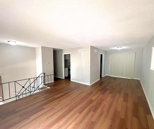 spare room with a textured ceiling and dark hardwood / wood-style floors