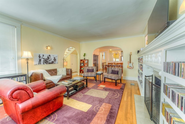 living room with light hardwood / wood-style flooring, a tile fireplace, and crown molding