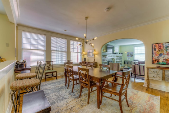 dining area with ornamental molding, a chandelier, and light hardwood / wood-style floors