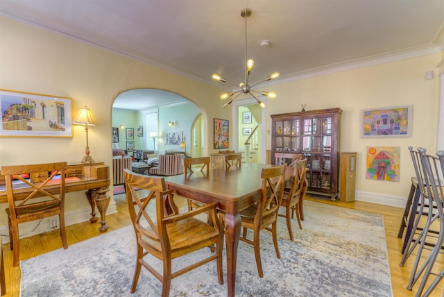 dining area featuring ornamental molding, light hardwood / wood-style floors, and a notable chandelier