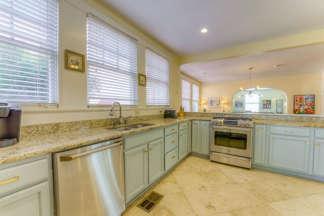 kitchen with light stone counters, sink, decorative light fixtures, stainless steel appliances, and crown molding