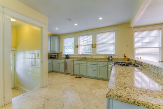 kitchen featuring light stone counters, sink, ornamental molding, tasteful backsplash, and stainless steel appliances