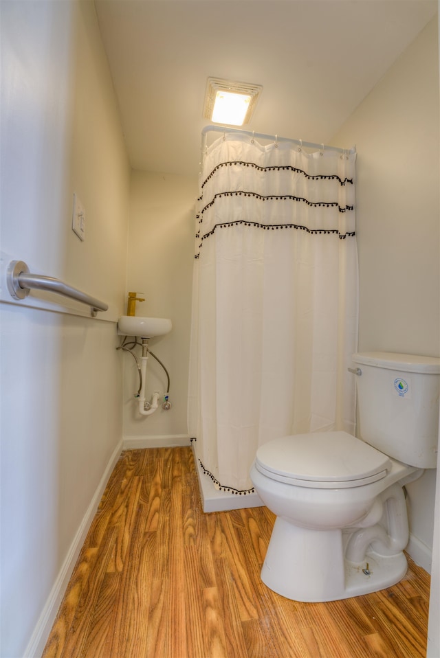 bathroom with toilet, a shower with shower curtain, and hardwood / wood-style flooring