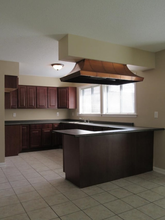 kitchen with a textured ceiling, kitchen peninsula, and light tile patterned flooring