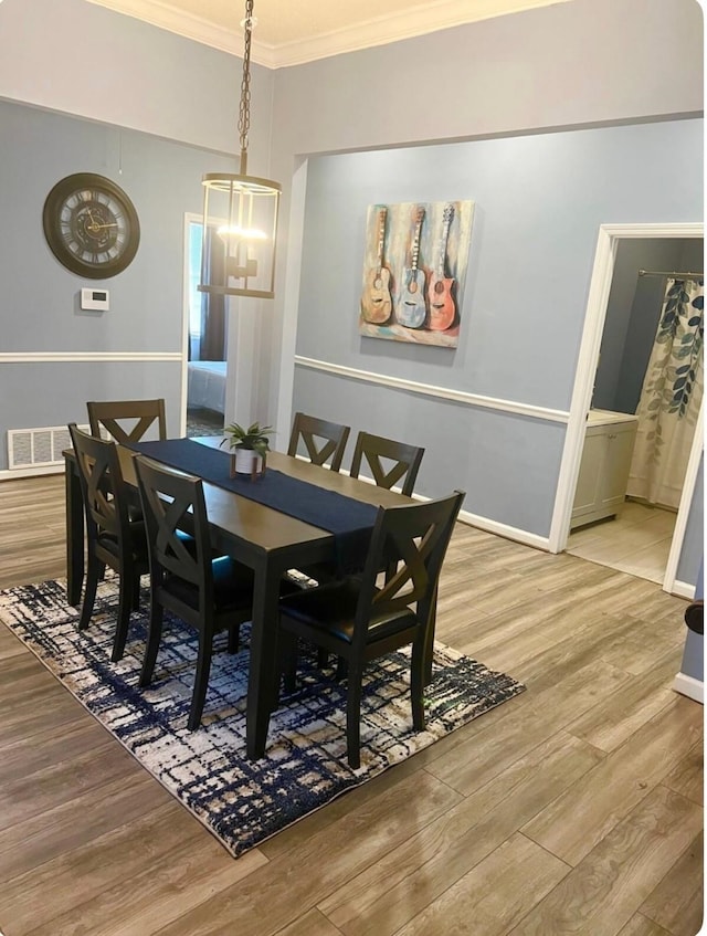 dining space with light hardwood / wood-style flooring and crown molding