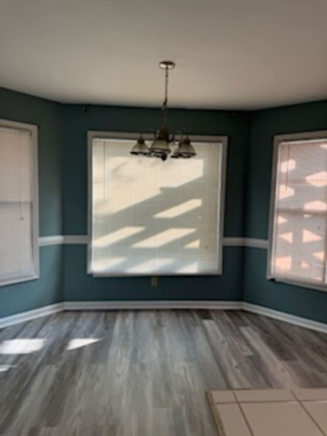 unfurnished dining area with plenty of natural light, a chandelier, and hardwood / wood-style flooring