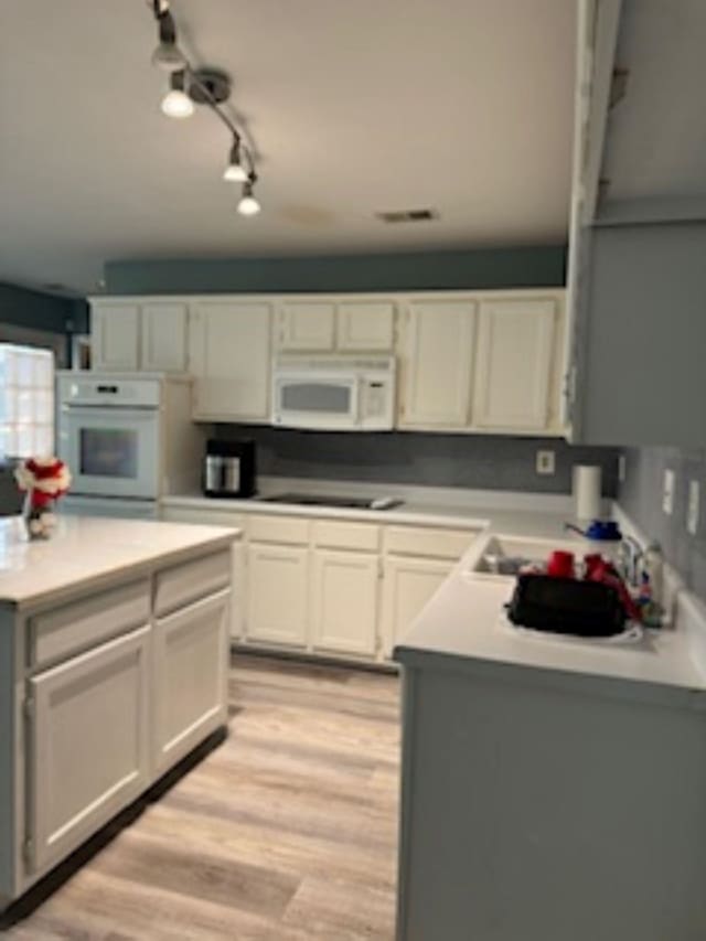 kitchen featuring light hardwood / wood-style flooring, white appliances, a center island, and white cabinetry