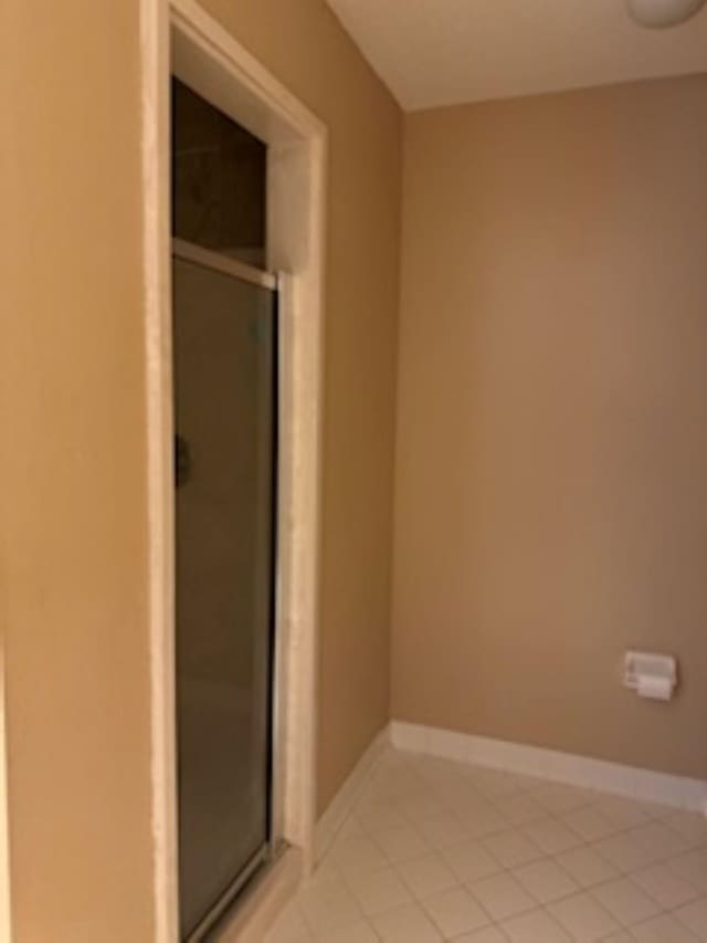 bathroom with an enclosed shower and tile patterned floors