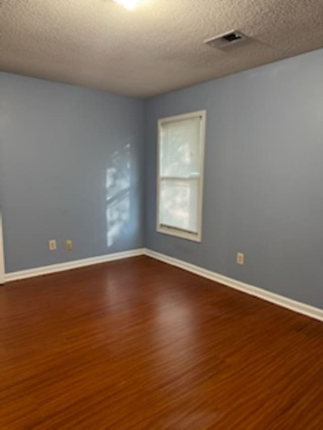 empty room with a textured ceiling and hardwood / wood-style flooring