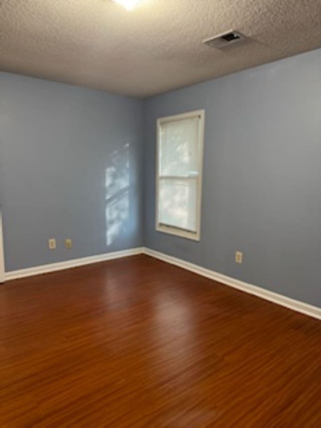 7565 Wintergreen Ln NW, Tn, TN 38018 - spare room featuring visible vents, baseboards, a textured ceiling, and wood finished floors