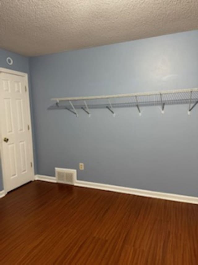7565 Wintergreen Ln NW, Tn, TN 38018 - unfurnished room with visible vents, baseboards, a textured ceiling, and dark wood finished floors