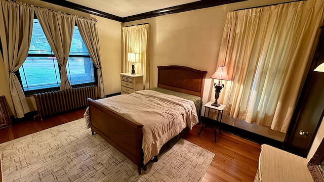 bedroom featuring radiator heating unit, crown molding, and hardwood / wood-style floors