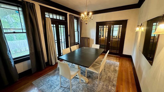 dining area with dark hardwood / wood-style flooring, french doors, a notable chandelier, and ornamental molding