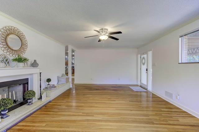 unfurnished living room featuring a textured ceiling, crown molding, light hardwood / wood-style floors, and ceiling fan