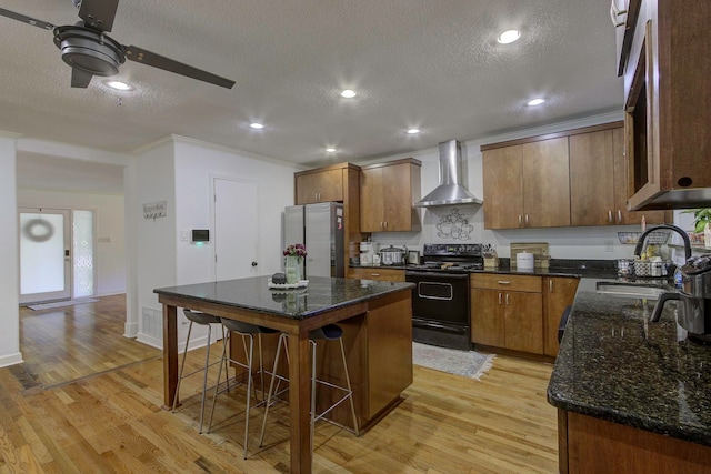 kitchen featuring stainless steel fridge, light hardwood / wood-style floors, ceiling fan, sink, and electric range