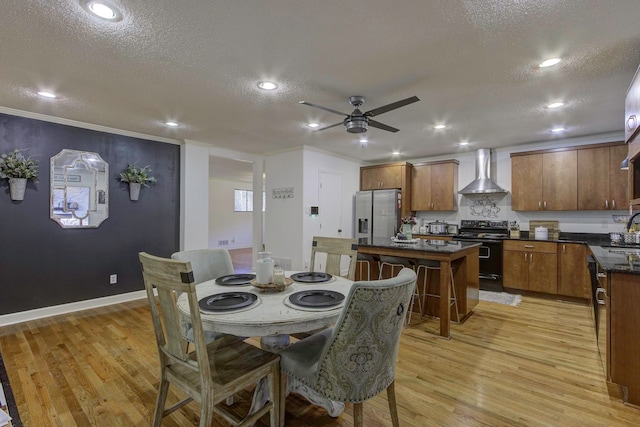 dining room featuring a textured ceiling, sink, light hardwood / wood-style flooring, ornamental molding, and ceiling fan