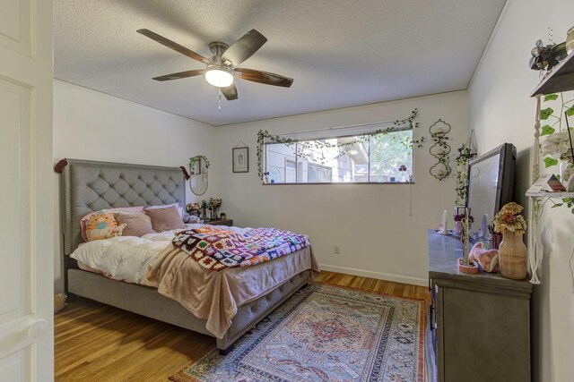 bedroom featuring ceiling fan, hardwood / wood-style floors, and a textured ceiling