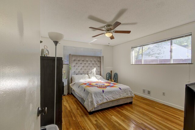 bedroom featuring a textured ceiling, wood-type flooring, and ceiling fan