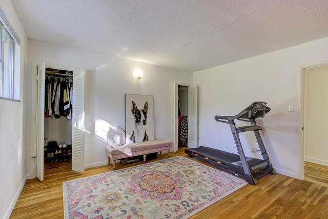 workout area with light hardwood / wood-style flooring and a textured ceiling