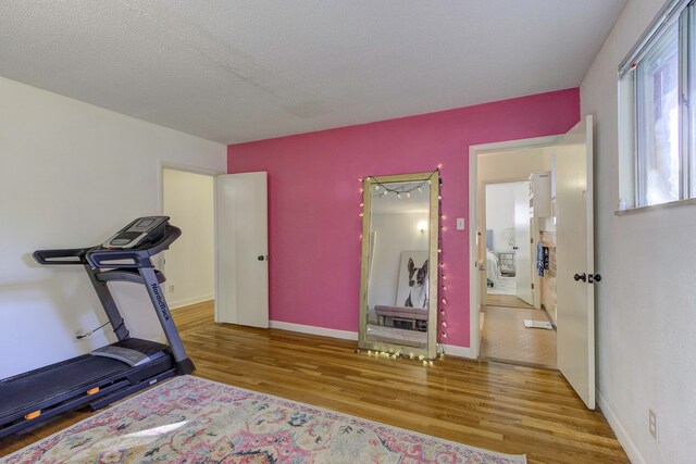 exercise area with light wood-type flooring and a textured ceiling