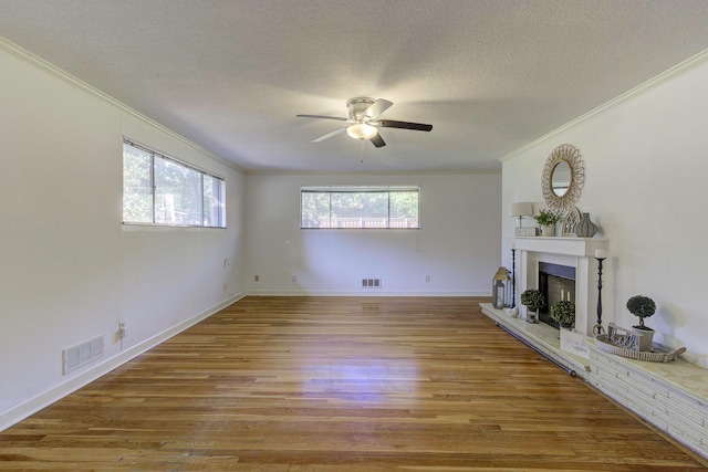 unfurnished living room featuring a textured ceiling, light hardwood / wood-style floors, ornamental molding, and ceiling fan