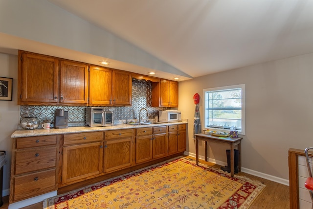 kitchen with tasteful backsplash, brown cabinetry, white microwave, and a sink