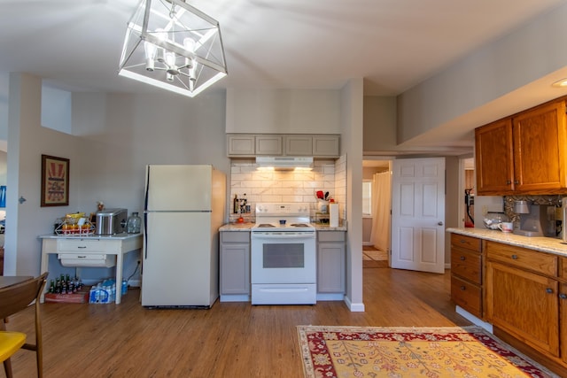 kitchen featuring light wood finished floors, backsplash, white appliances, brown cabinets, and range hood