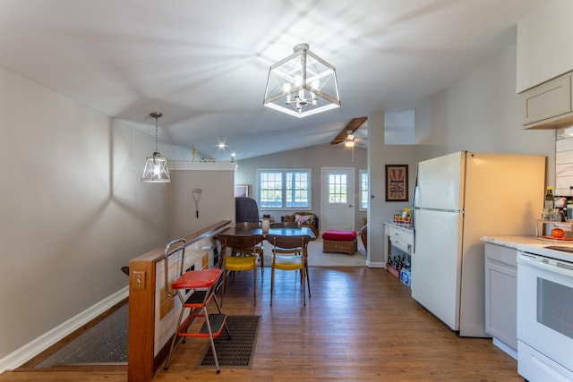 kitchen with pendant lighting, white appliances, dark wood-type flooring, ceiling fan with notable chandelier, and vaulted ceiling