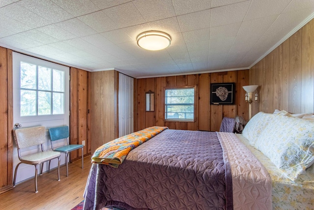 bedroom with wooden walls, wood finished floors, and crown molding