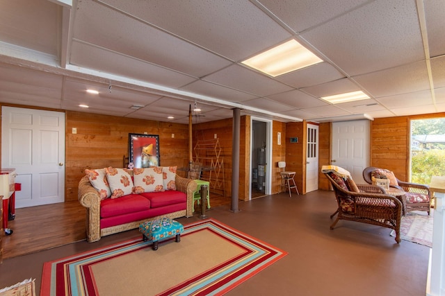 living room with wood walls and a drop ceiling