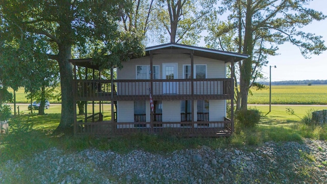 back of property with a deck and a lawn