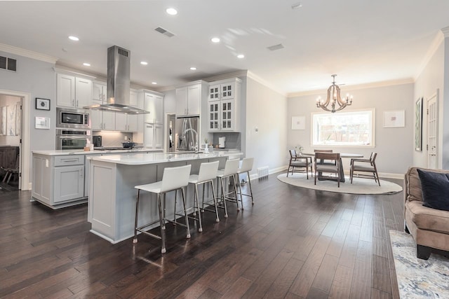 kitchen with white cabinets, stainless steel appliances, wall chimney exhaust hood, and ornamental molding