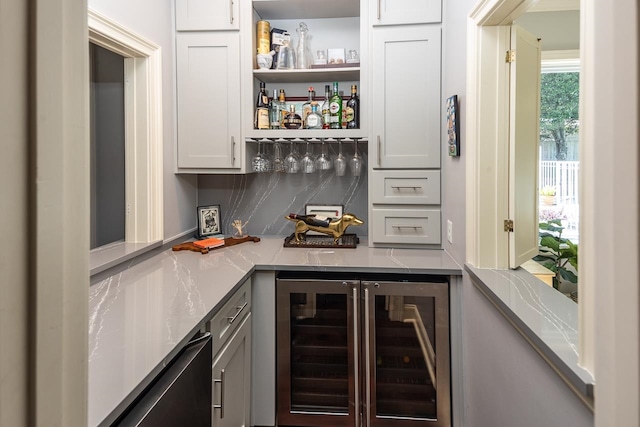 bar with backsplash, white cabinetry, light stone countertops, and wine cooler