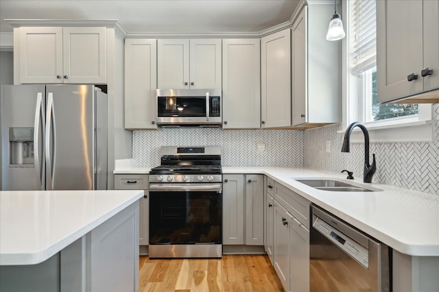 kitchen featuring light countertops, a sink, appliances with stainless steel finishes, and light wood-type flooring