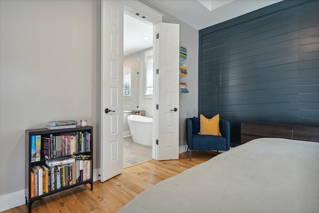 bedroom featuring connected bathroom and hardwood / wood-style flooring