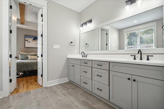 bathroom featuring double vanity, a sink, connected bathroom, and baseboards