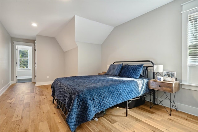 bedroom featuring multiple windows, wood-type flooring, and lofted ceiling