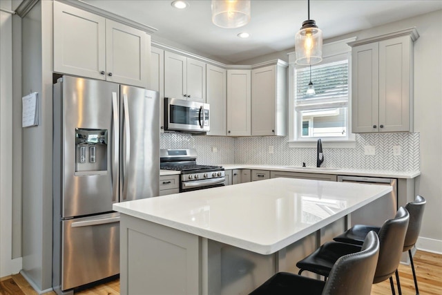 kitchen with light hardwood / wood-style floors, stainless steel appliances, a center island, decorative light fixtures, and sink