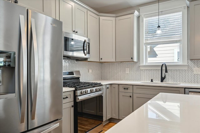 kitchen featuring light countertops, a sink, hanging light fixtures, stainless steel appliances, and decorative backsplash