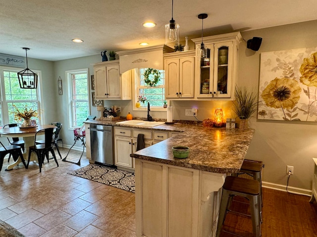 kitchen featuring hanging light fixtures, kitchen peninsula, a textured ceiling, stainless steel dishwasher, and sink