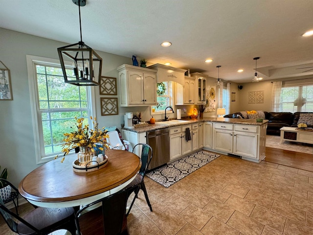 kitchen with pendant lighting, stainless steel dishwasher, kitchen peninsula, and a healthy amount of sunlight