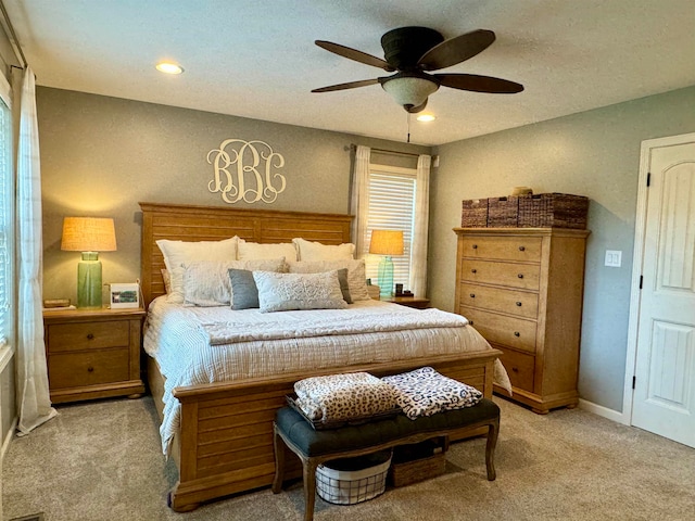 bedroom featuring ceiling fan, light colored carpet, and multiple windows