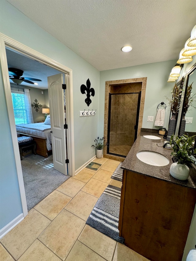 bathroom featuring ceiling fan, vanity, a textured ceiling, walk in shower, and tile patterned flooring