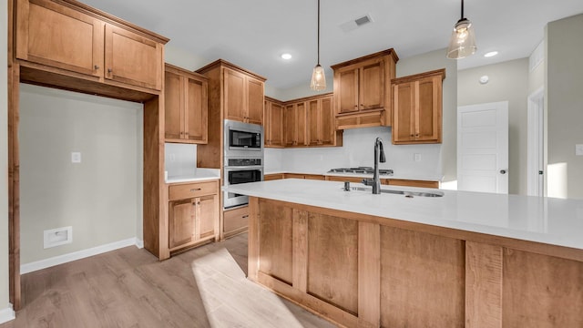 kitchen with sink, pendant lighting, light wood-type flooring, and appliances with stainless steel finishes